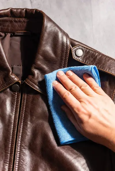Person wiping a leather jacket with a dry cloth close-up